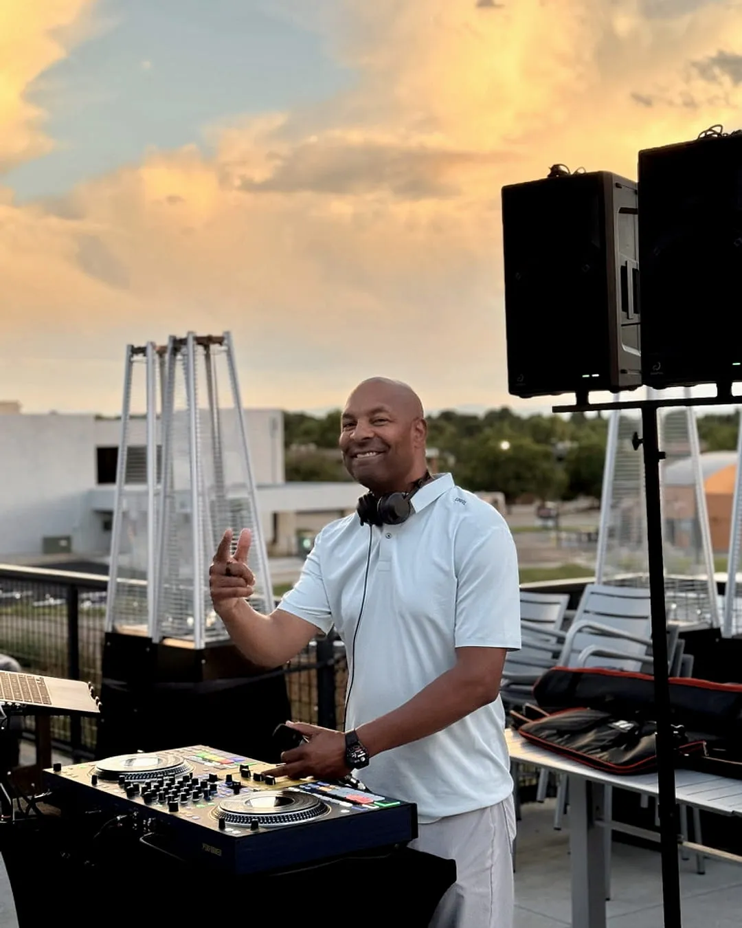 Mike Broom smiling behind the decks during a sunset set at The Rouge, flashing a peace sign at the camera